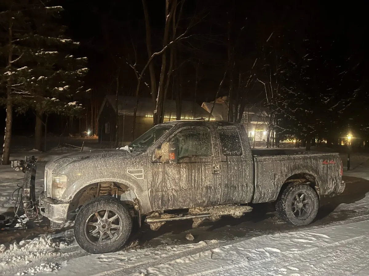 Plow truck mid-job at night in snowstorm
